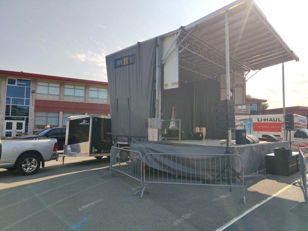 Scène mobile installée à côté de la remorque Power Pack 100K d'Eco Location lors d'un événement extérieur
